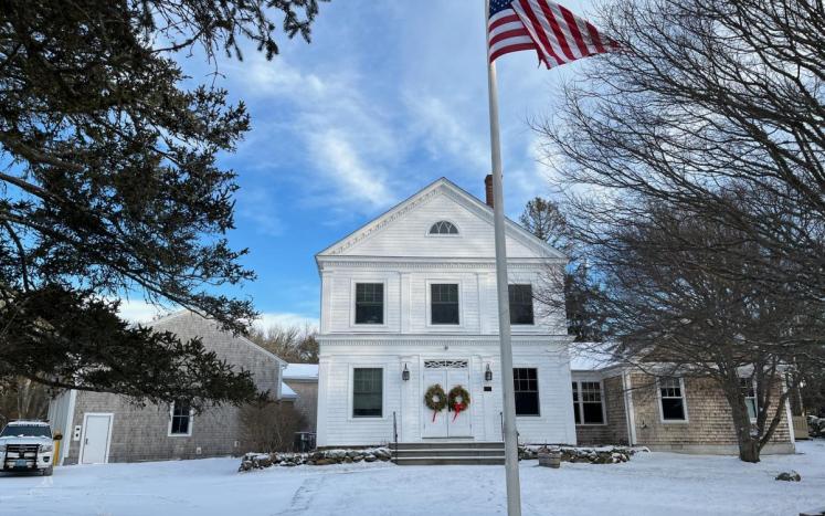 view of gable end of Chilmark town hall with American flag on pole in the foreground